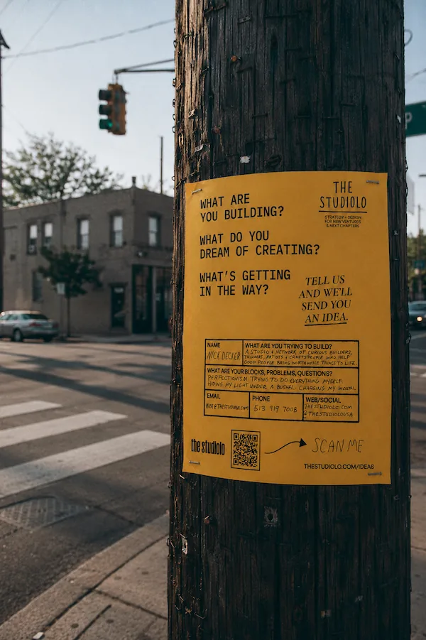 A Studiolo flyer taped to a telephone pole at a street corner, its questions and blank form facing the sidewalk.